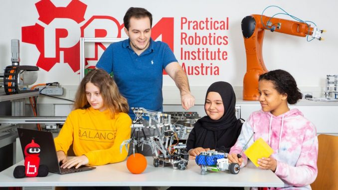 V.l.n.r.: Alexa, Berra und Kelly werken am "Robotics Day Vienna" an einem Roboterkran, der schon ein wenig Intelligenz besitzt: Man kann und soll ihn programmieren. Wie das geht, zeigt Stefan Polydor vom Practical Robotics Institute Austria (hinten).