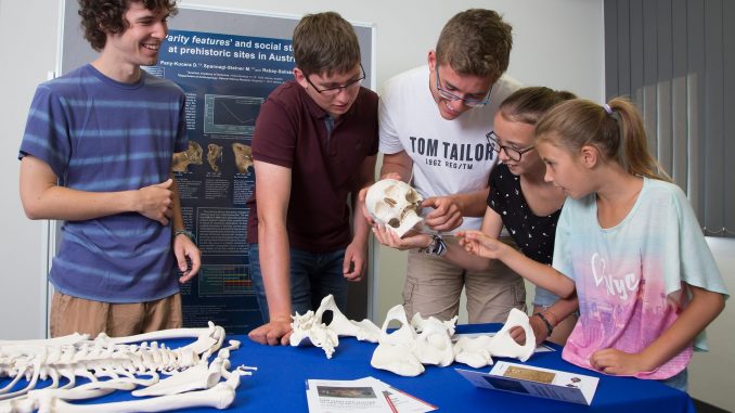 V.l.n.r.: Lukas Waltenberger vom Archäologie-Institut der Akademie der Wissenschaften zeigt Rene (17), Harald (17), Sophie (13) und Michelle (9) seine lebensechten Modelle von Menschenknochen. Das Institut untersucht, wie Mütter in der Steinzeit lebten. Die jungen Besucher der "European Researchers' Night 2018" können an Becken und Schädel erkennen, ob die Knochen von einer Frau oder einem Mann stammen.