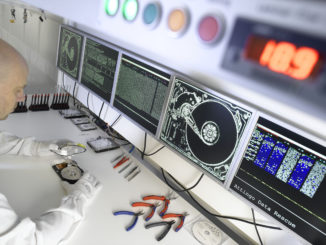 Ein Techniker im Attingo-Reinraumlabor untersucht eine offene Festplatte.